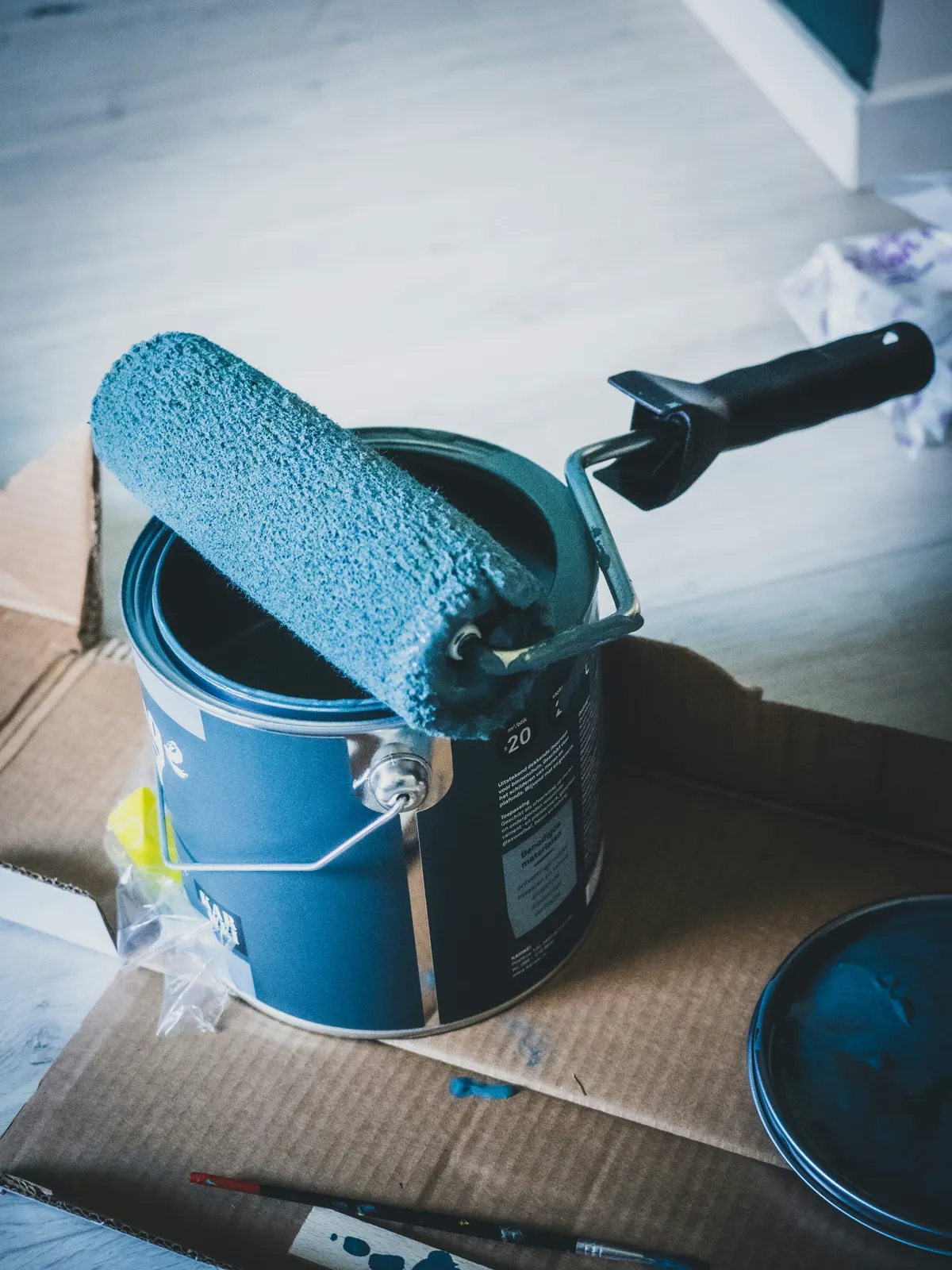 Farbwalze liegt auf einem geöffneten blauen Farbeimer